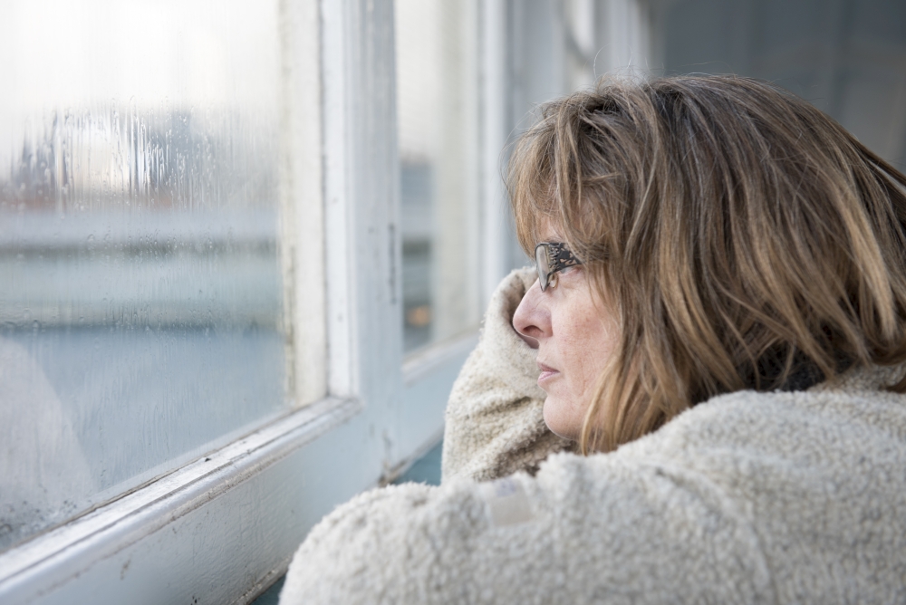 mature woman looking out of the window on a rainy miserable day